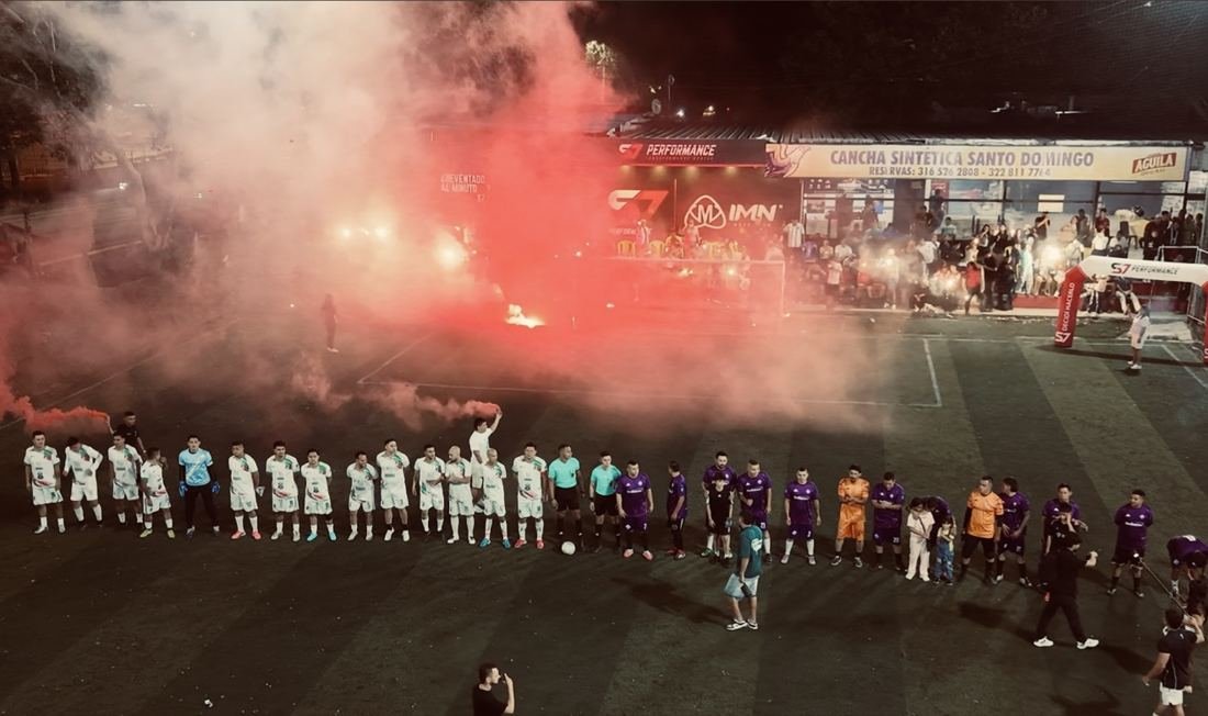 Los dos equipos formados antes del himno, con la tribuna encendida